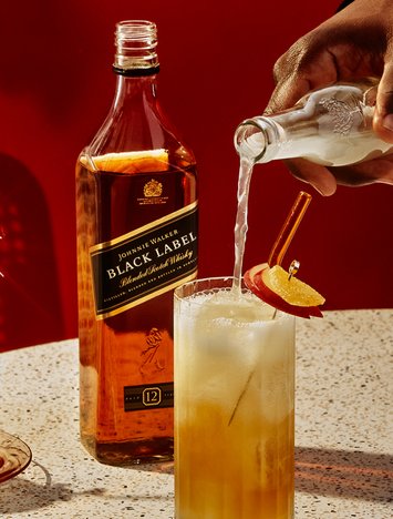 Customer pouring a mixer into a Johnnie Walker Black Label cocktail
